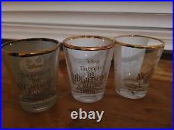 Shot glass display case and three shot glasses with gold around the top